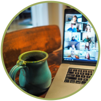A laptop open to a Zoom meeting sitting on a table next to a teal coffee mug.