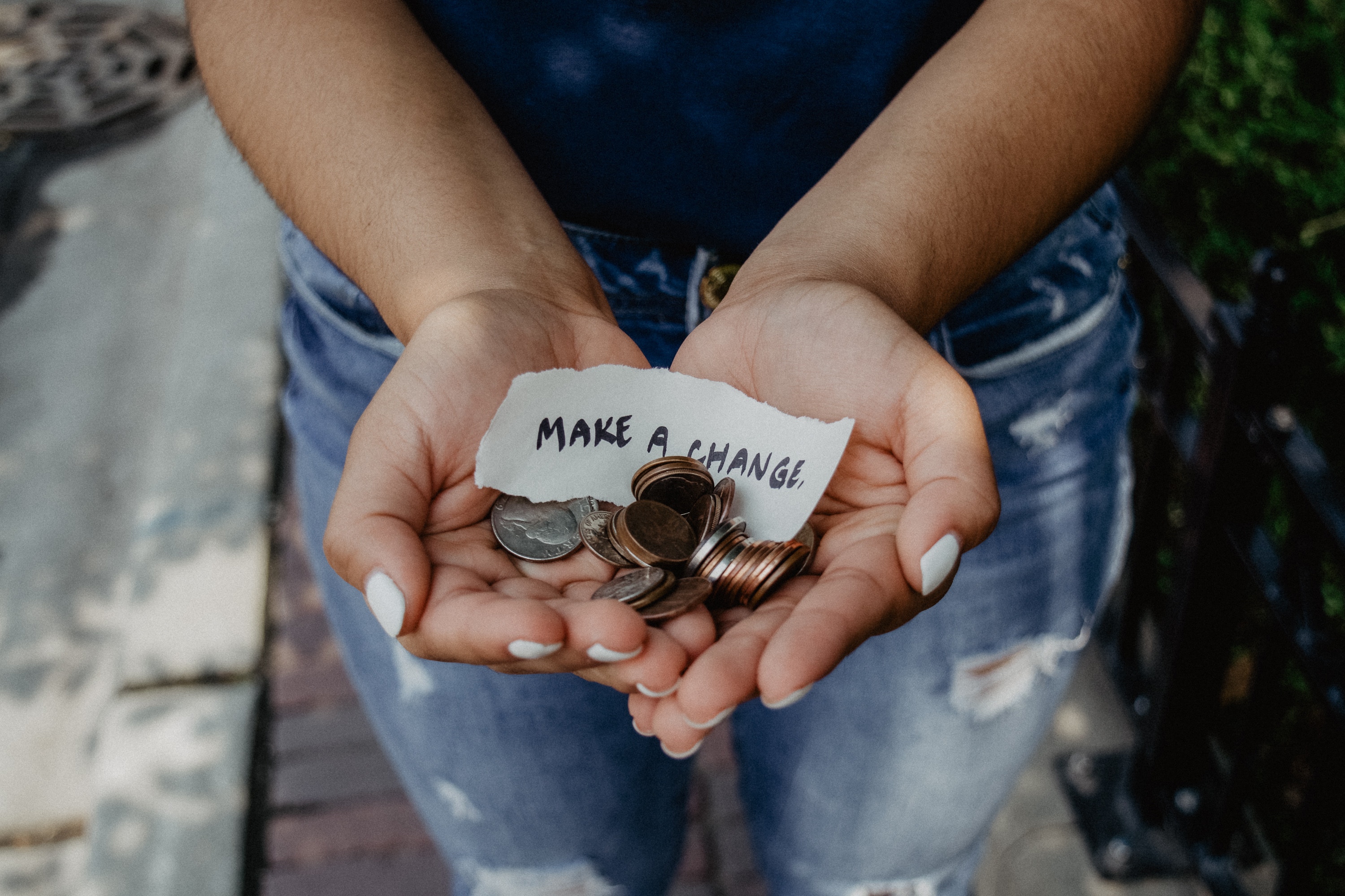 Hands holding a pile of change with a slip of paper reading "Make a change"